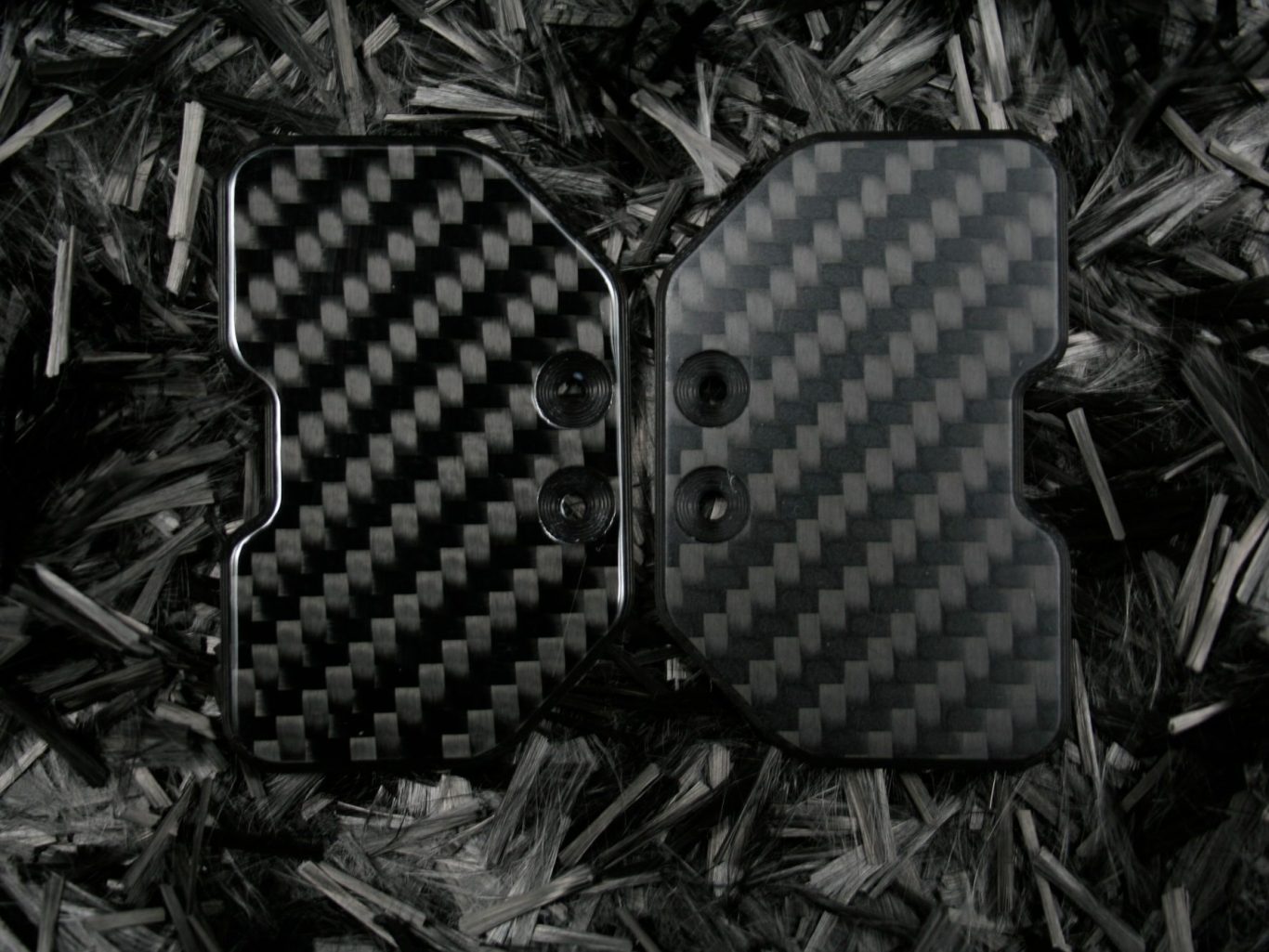 Zwei schwarze Carbon-Schaltwippen mit strukturierter Oberfläche auf dunklem Hintergrund.